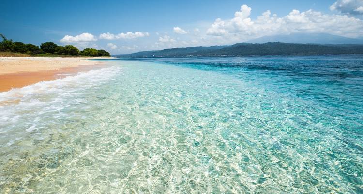 Clear tropical beach with turquoise waters and blue skies.