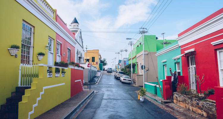 Bâtiments colorés sur une rue avec des voitures garées.