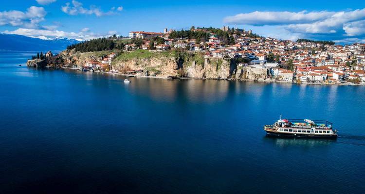 Ein Boot, das in der Nähe einer Küstenstadt mit Klippen segelt.
