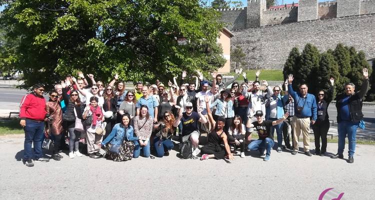 Große Gruppe von Menschen, die draußen in einem sonnigen Bereich posiert.