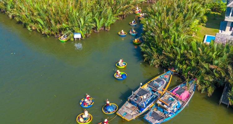 Vue aérienne de bateaux paniers ronds et colorés naviguant à travers une forêt de cocotiers aux eaux vertes près de Hoi An.
