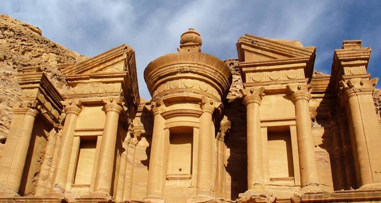 Architecture rupestre ancienne avec colonnes classiques et sculptures.