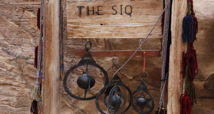 Houten richtingbord dat naar de Siq wijst tegen gestructureerde zandste