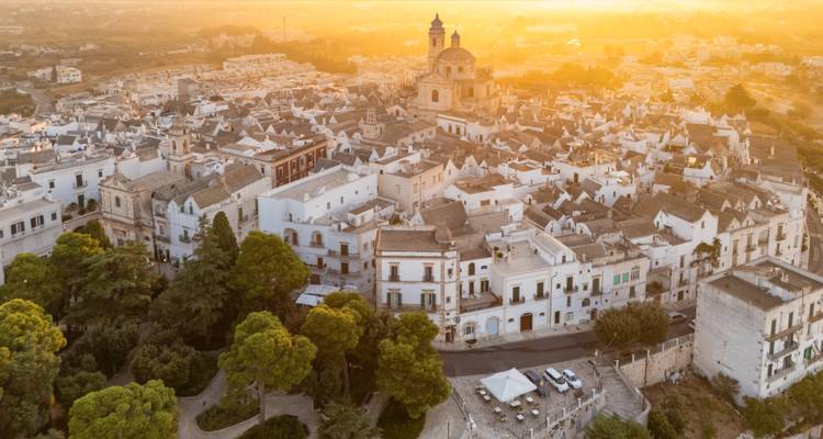 El dorado amanecer baña el pueblo blanco en la ladera con la cúpula de la iglesia entre los tejados que se extienden por todas partes