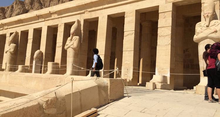 Ancient Egyptian temple facade with people walking.