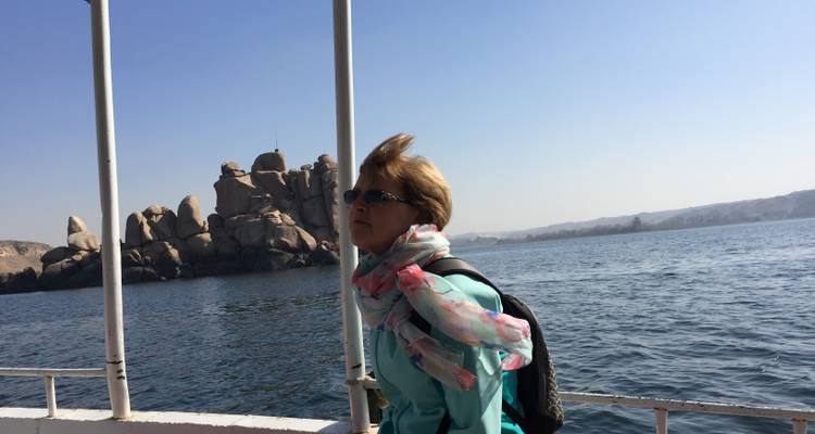 A person on a boat with rocky formations in the background.