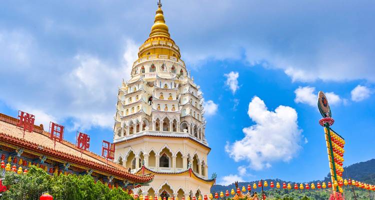 De kleurrijke Kek Lok Si pagode rijst op tegen een helder blauwe lucht versierd met lantaarns.