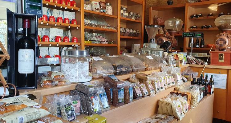 Intérieur d'une boutique avec des étagères de produits, incluant des bouteilles, des sacs d'herbes et des contenants.