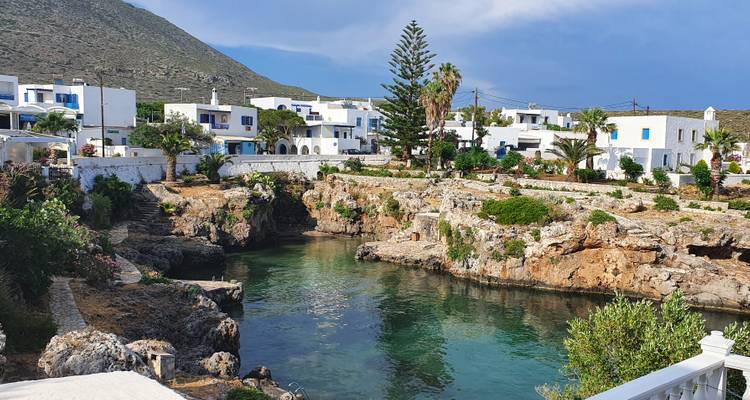Vue panoramique de bâtiments blancs au bord d'une côte rocheuse avec de l'eau turquoise.