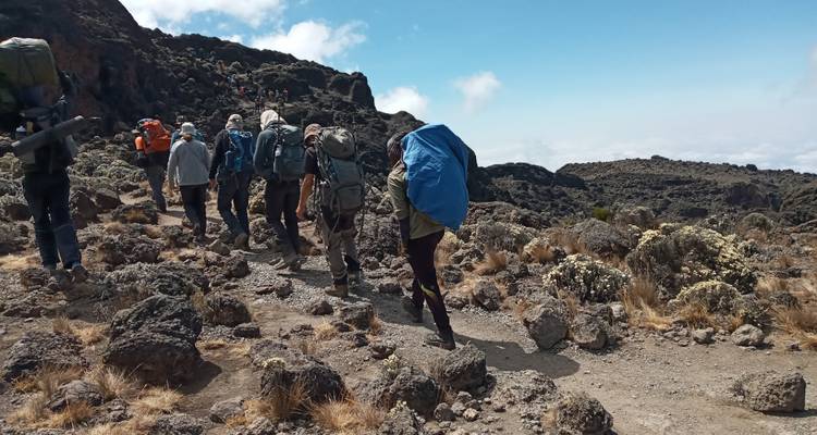 Groep wandelaars die over een rotsachtig bergpad lopen.