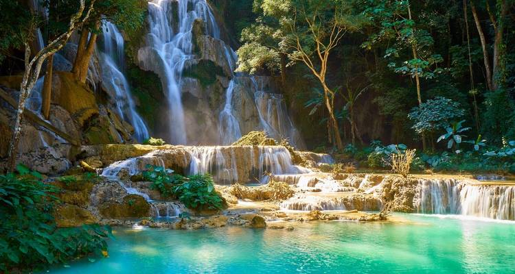 Een prachtige waterval die neerstort in turquoise poelen, omringd door weelderig groen.