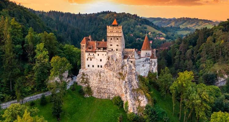 Sprookjesachtig Bran Castle op een rotsachtige klif omgeven door dicht Transsylvaans bos bij zonsondergang