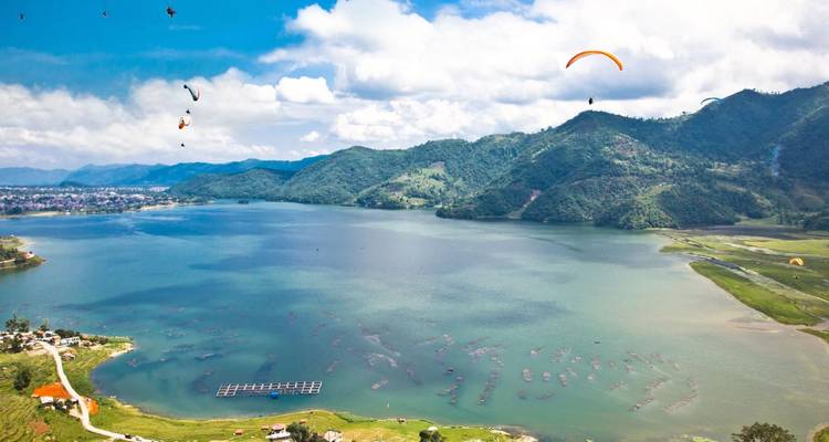 Meer met paragliders in de lucht erboven.