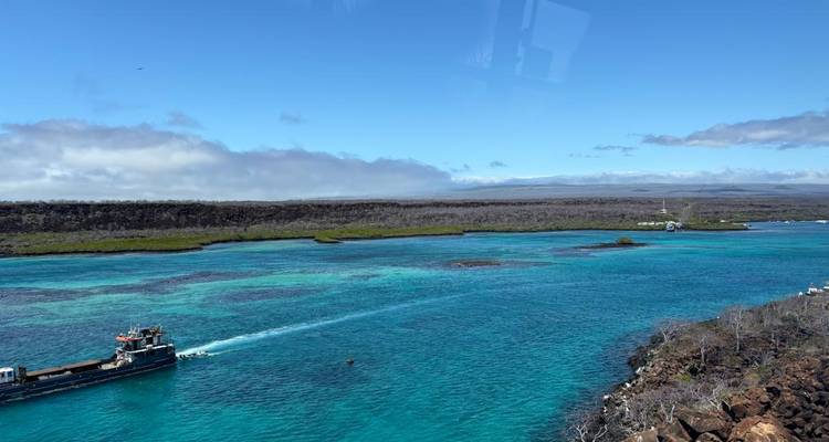 Canal turquoise avec petit bateau de travail et côte volcanique sous un ciel bleu