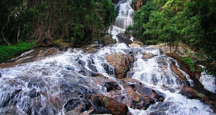 Waterfall cascading down rocky terrain in a lush green setting.