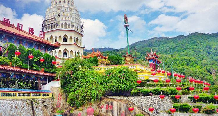 Intricate temple with colorful facades and lanterns in a lush environment.