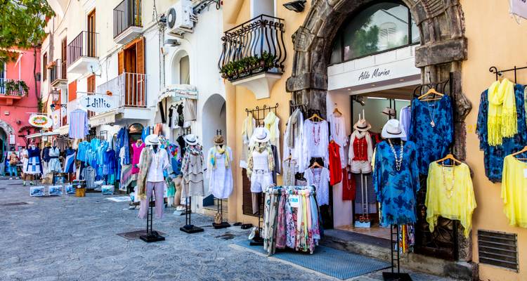 Colorful boutique storefronts displaying stylish resort wear along a pedestrian street.
