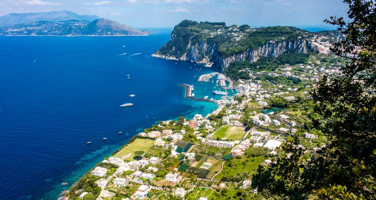 Indrukwekkend luchtfoto van het eiland Capri met witgekalkte gebouwen, dramatische kliffen en de diepblauwe Middellandse Zee bezaaid met jachten.
