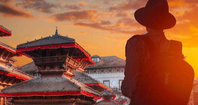 Toerist met een hoed die traditionele tempels bekijkt bij zonsondergang.