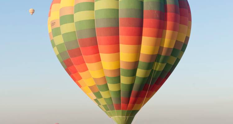 Montgolfière colorée dans le ciel avec d'autres ballons au loin.