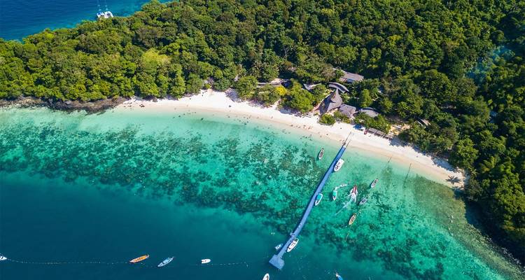 Luchtfoto van een strand met boten en helder water.