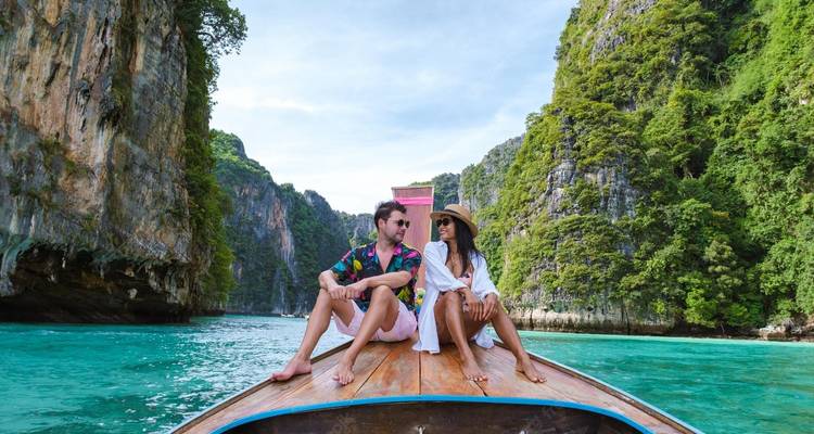 Een stel zittend op een boot op een schilderachtige locatie met kliffen eromheen.