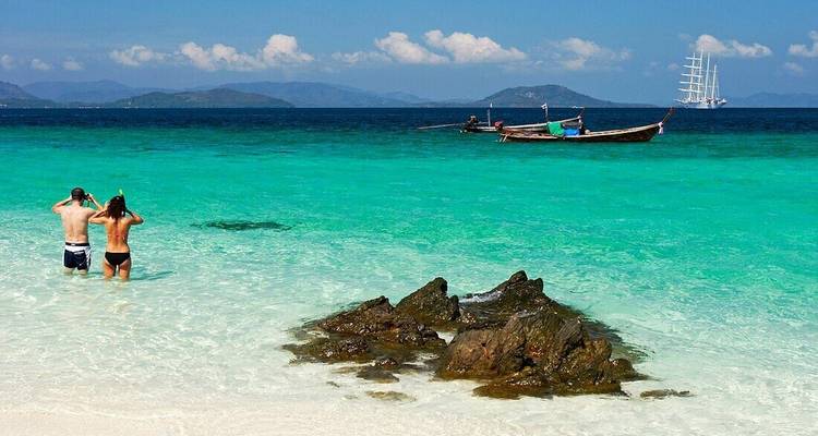 Toeristen die genieten van het heldere blauwe water van een tropisch strand.