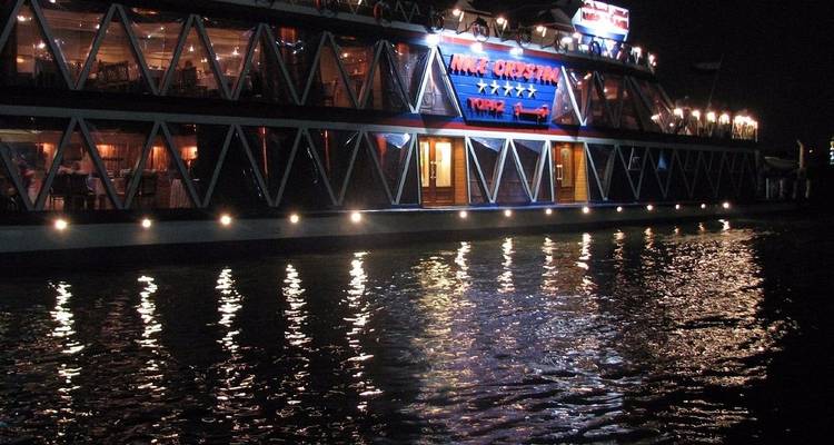 Vista exterior de un crucero de noche con reflejos en el agua.