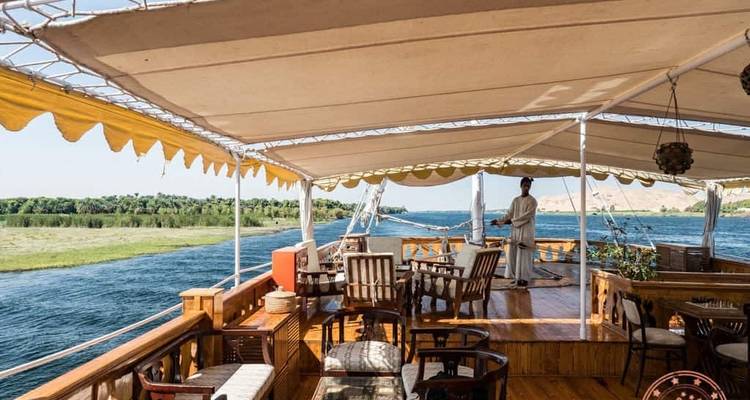 Cubierta abierta de un crucero con toldo y vista al río.