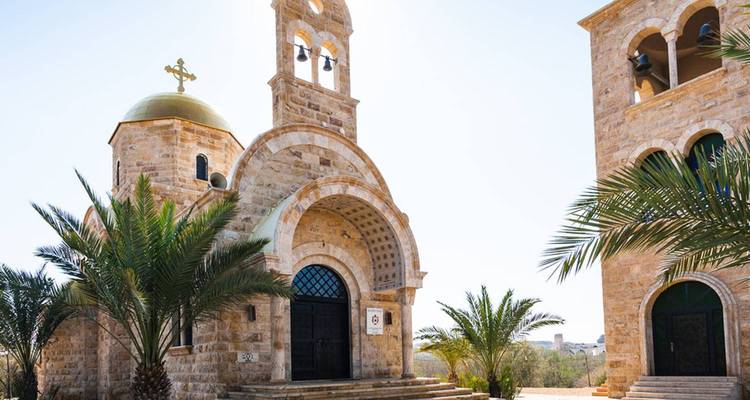 Una iglesia cristiana con una cúpula dorada y campanario, con palmeras.