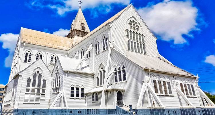 Gran edificio de iglesia de madera blanca bajo un cielo azul.