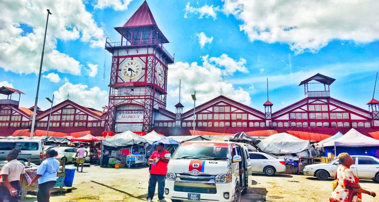 Mercado lleno de gente con una torre del reloj.