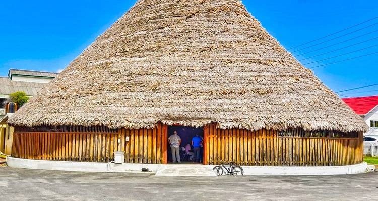 Edificio tradicional con techo de paja y dos personas afuera.