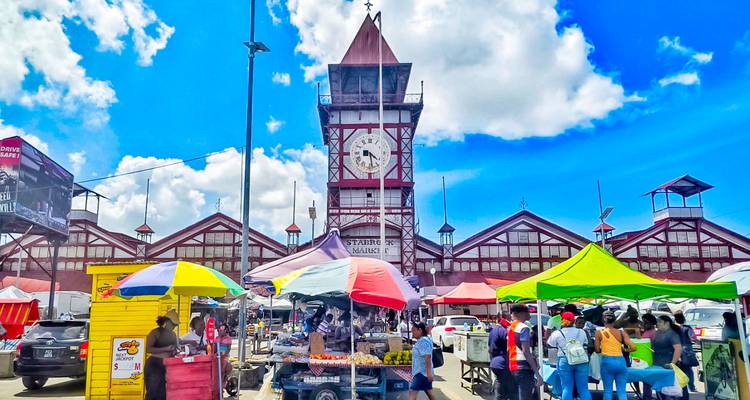 Marché avec des étals colorés et une tour d'horloge.