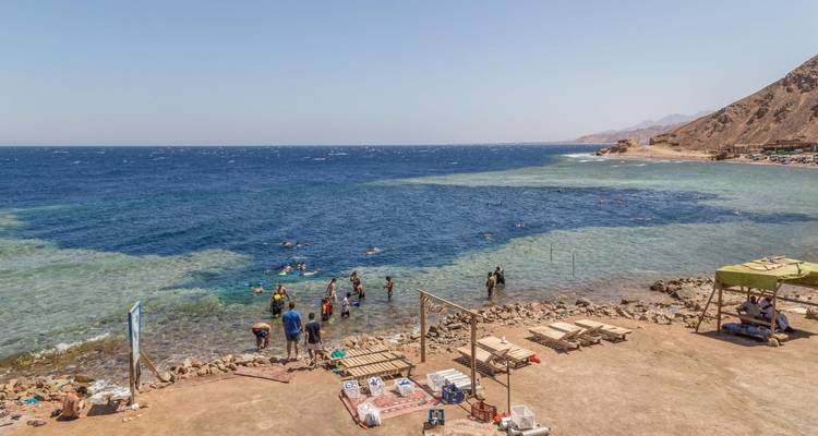 Snorkelaars plonzen in het heldere water van het beroemde Blue Hole met een levendig koraalrif vlakbij.