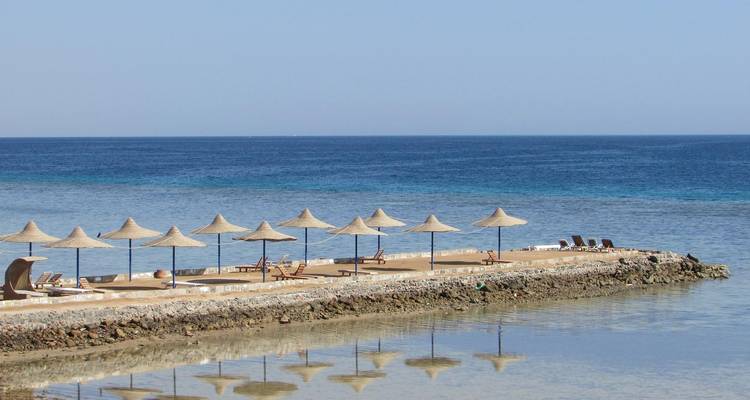 Strand mit Sonnenschirmen und Liegestühlen am Meer.