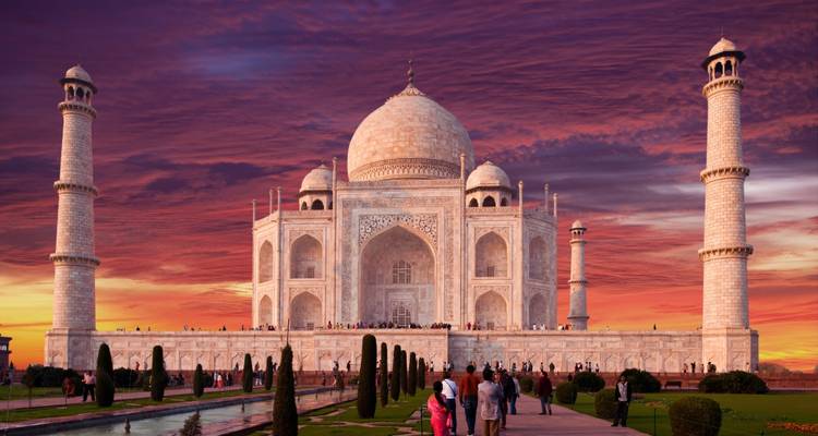 Taj Mahal bei Sonnenuntergang mit Menschen im Vordergrund.