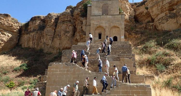 Des touristes gravissant une structure à gradins sur un fond rocheux.