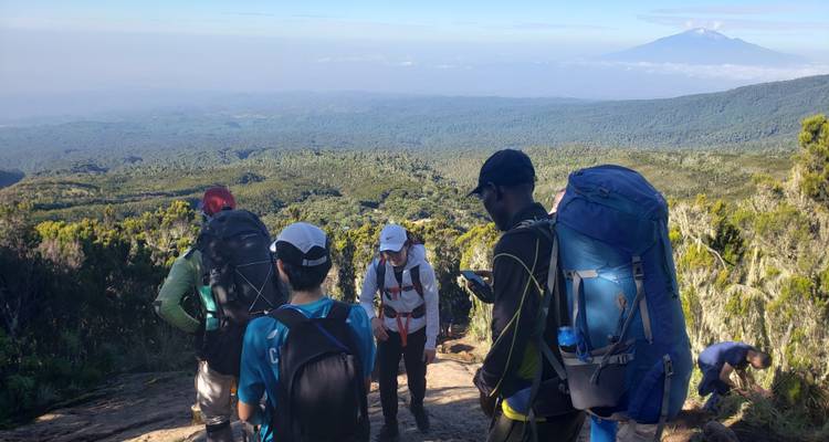 Wandelaars die rusten op een pad met uitzicht op bergen in de verte.