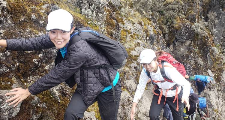 Twee wandelaars die een rotsachtig terrein beklimmen.