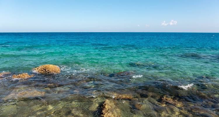 Clear blue sea with visible rocks and a distant horizon.