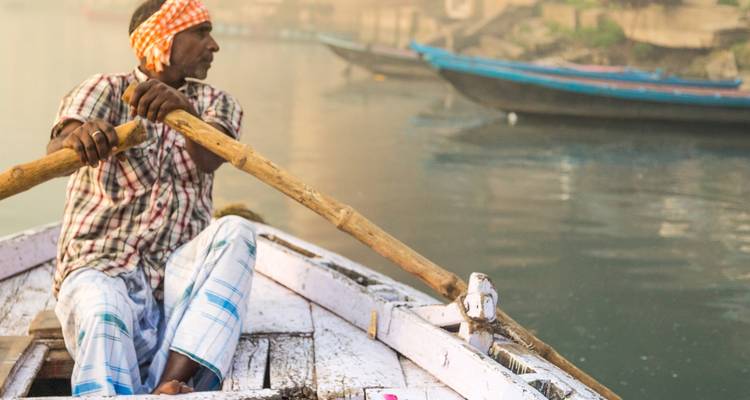 Personne ramant dans un bateau sur une rivière avec d'autres bateaux à proximité.