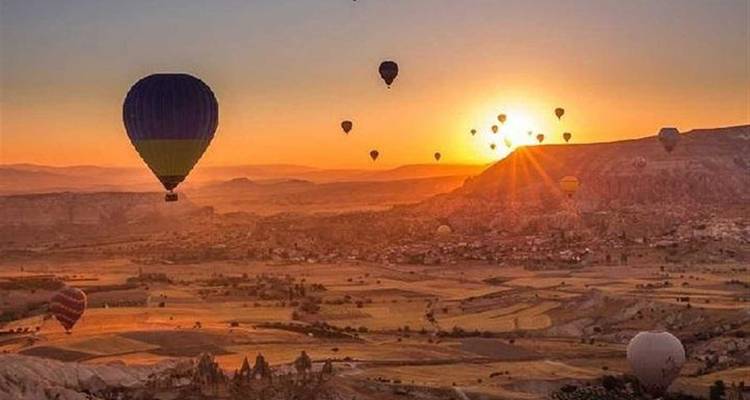 Globos de aire caliente elevándose sobre un paisaje desértico al amanecer.