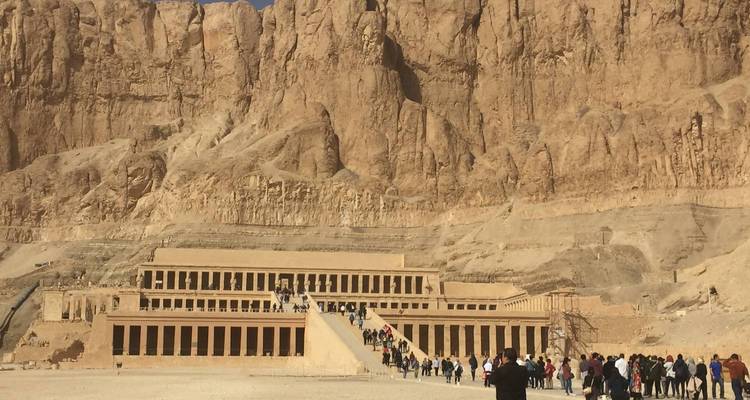 Une file de touristes s'approche du Temple d'Hatchepsout, adossé à la falaise, par une journée ensoleillée.