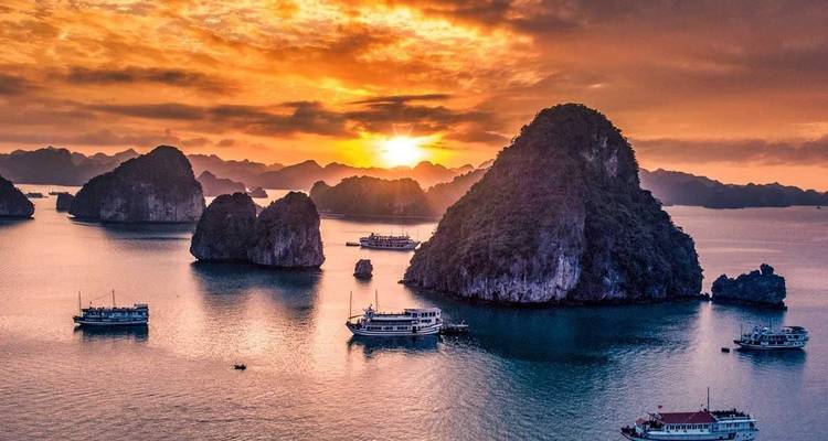 Prachtige zonsondergang boven Halong Bay met boten en kalkstenen karsten.