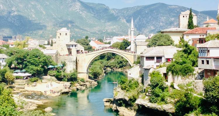 Historic bridge over a river flowing through a vibrant town.