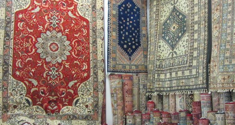 Ausstellung von kunstvollen, farbenfrohen marokkanischen Teppichen und gerollten Teppichen in einem traditionellen Geschäft.