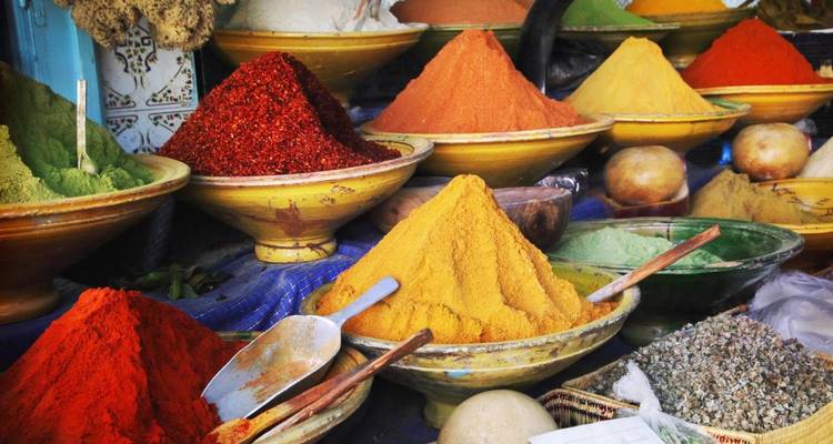 Hoch aufgetürmte Haufen leuchtend bunter Gewürze in Keramikschalen auf einem marokkanischen Souk.