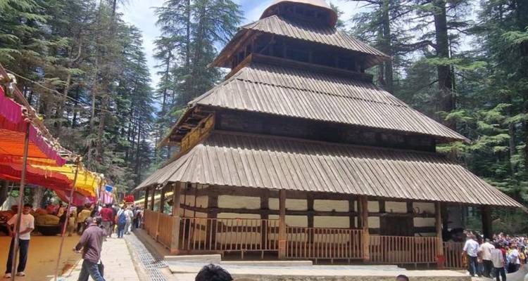 Traditional Hadimba Temple made of wood with festival stalls and visitors around.