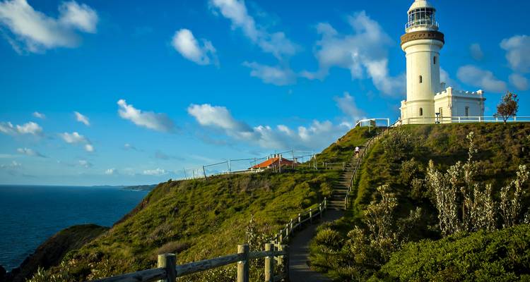 Escena costera con un faro sobre una colina cubierta de hierba.